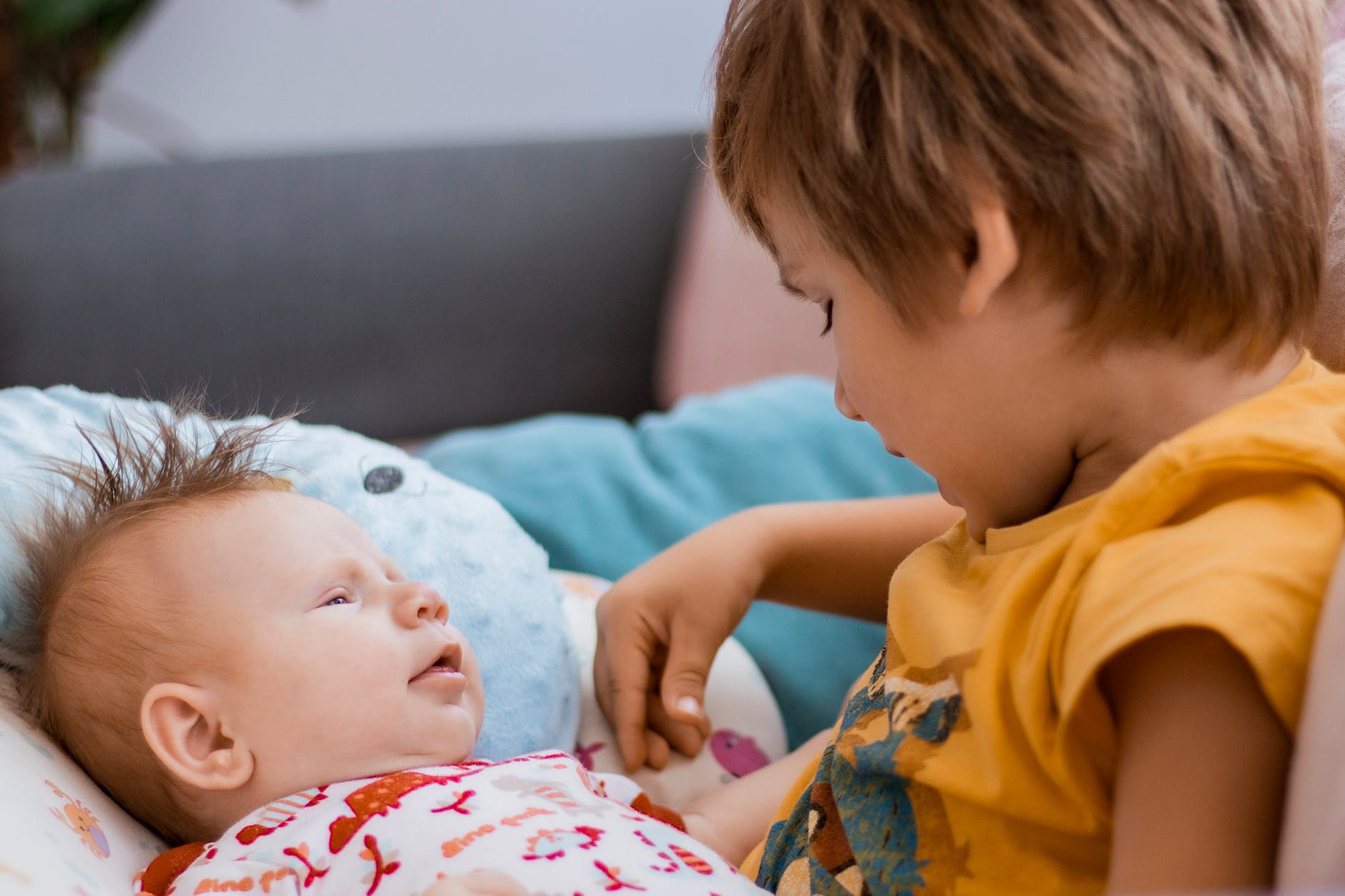 boy in yellow shirt watching a baby